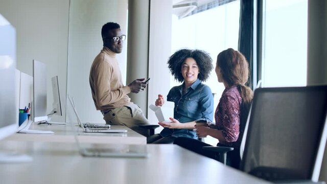Video of three multiethnic entrepreneurs talking while taking a break and eating in the work place at coworking place.