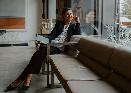 Portrait of smiling businesswoman sitting on sofa at office
