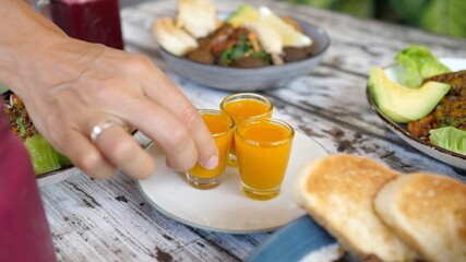 Hand picking a glass with organic orange spirulina shot 