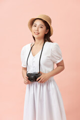 Young beautiful teen female in straw hat holding camera smiling happy, over pink background