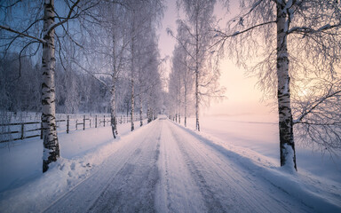 Scenic snow landscape with beautiful sunrise and snowy road at winter morning in Finland - 426589021