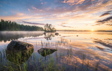 Scenic nature landscape with mood fog and beautiful sunrise at early summer morning in lakeside Finland - 426589035