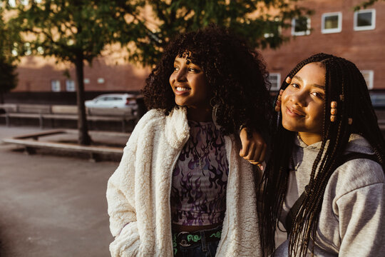 Smiling female teenager friends standing on footpath