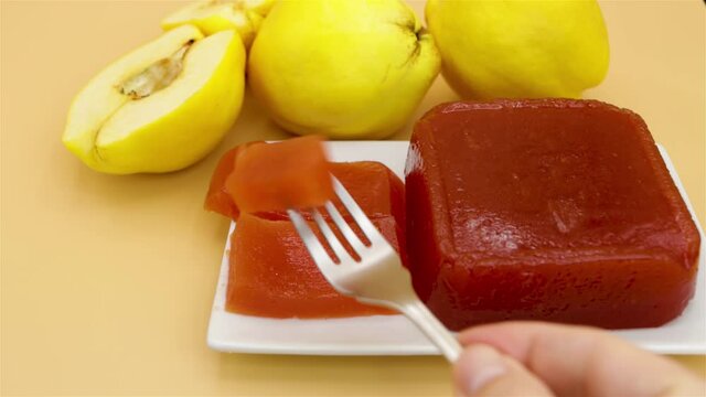 Showing a delicious homemade quince jam, homemade quince flesh, on a creamy background, with quinces out of focus in the background