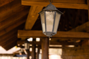 A vintage black lamp under the ceiling in a wooden farmhouse. Old-fashion lamp. Copy space.