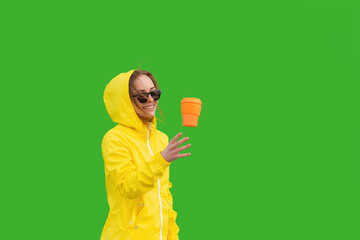 A woman in a raincoat throws a reusable cup. The woman is ready for new ideas with a delicious drink