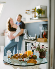 selective focus. Gentle woman and man in white clothes looking at each other with love sitting in light room with breakfast meal on table