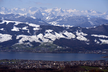 Panoramic landscape with lake Zurich and snow capped Swiss alps in the background. Photo taken April 8th, 2021, Zurich, Switzerland.