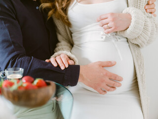 Close up of a couple holding their hands on pregnancy belly