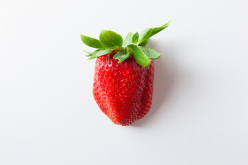 One red strawberry with green leaves on white background, top view