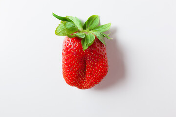 One red strawberry with green leaves on white background, top view