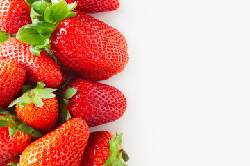 Bunch of red strawberries with green leaves on white background, top view, copy space on the right