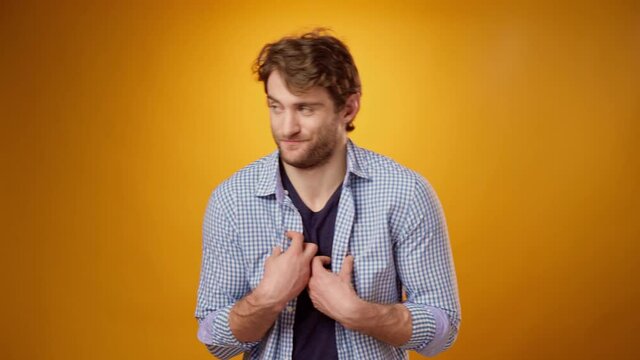 Confused young man gesturing "It's not me, it's not my fault", yellow background