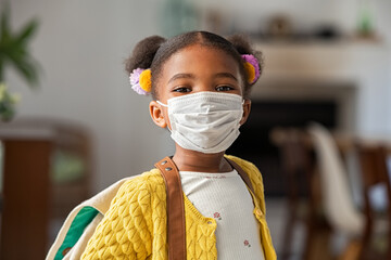 Cute little girl wearing face mask at home before going to school