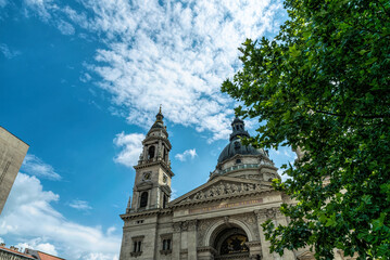 Fototapeta na wymiar Budapest, Hungary - July 14, 2019: majestic facade of the old St. Stephen's Basilica in Budapest and crowd of tourists on the street, Hungary. Great Catholic Cathedral, built in the Baroque style
