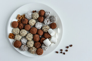 truffles with cocoa, coconut and sesame seeds with chocolate and marshmallows, delicious dessert on a white background
