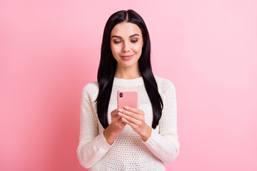Photo portrait of woman smiling browsing internet social media with cellphone isolated on pastel pink color background