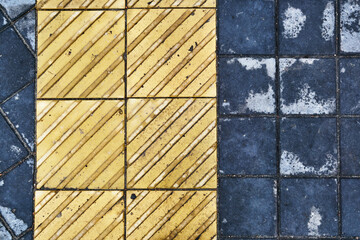 Background texture of square yellow tiles for the visually impaired and blind. Tactile stone street