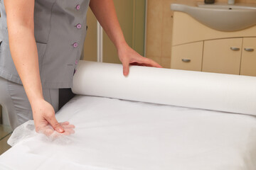 Professional masseuse covering massage table with disposable sheet