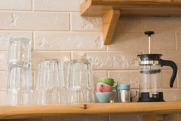 Wooden shelf on the wall with glasses, a jar, and a teapot