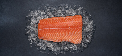Raw chilled salmon fillet on dark background with crushed ice. Healthy fresh seafood. Close-up top...