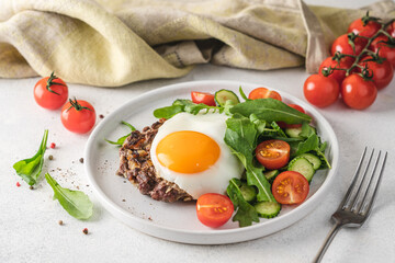 Chopped beef steak with fried egg and salad. Delicacy dinner in  plate on white background. Healthy food concept