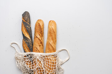 Fresh baguettes in mesh bag on white background. Long bread. Fresh traditional French  bakery...