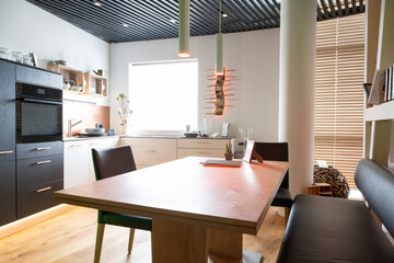 modern kitchen with wooden dining table and bench with window and black slatted ceiling