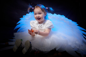 A beautiful cute blonde small girl with white wings looks like an nice young angel during photo...