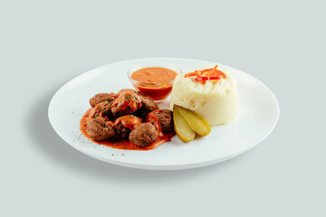 Meatballs with tomato sauces, mashed potatoes and pickles.