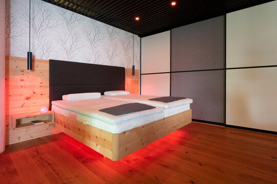 modern stone pine bed with led lighting, hanging lamps and black slatted ceiling