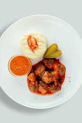 Meatballs with tomato sauces, mashed potatoes and pickles.