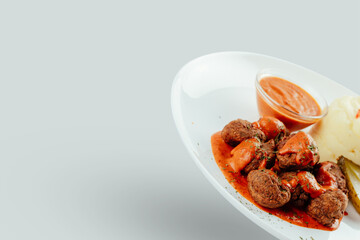 Meatballs with tomato sauces, mashed potatoes and pickles.