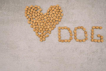 Dry dog ​​food, lined with hearts with the inscription dog on a gray background.
 Healthy balanced dog food. Pet care