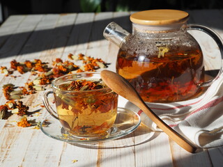 Dried flowers of calendula and marigolds on a wooden background. Medicinal herbal tea in a glass...