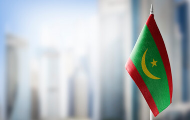 A small flag of Mauritania on the background of a blurred background