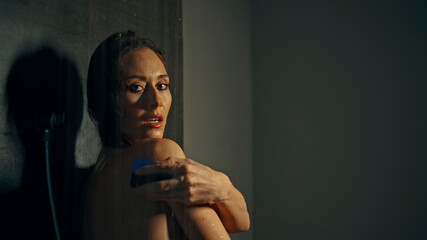 Young European girl long-haired brunette stands in a dark shower