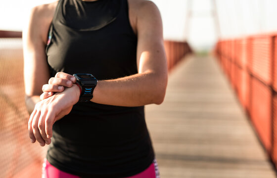 Female torso of a triathlete woman consults her statistics on her smart watch