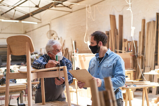 Craftsman senior and apprentice with face mask