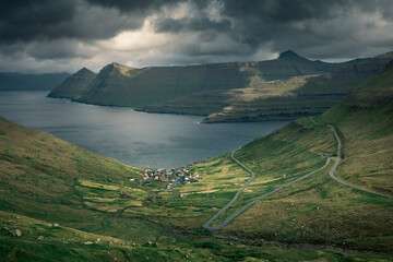Panoramic mountain landscape of Faroe Islands with village Funningur at the coast of island...
