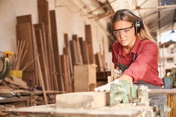 Woman as a carpenter trainee planing wood