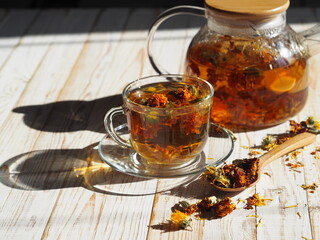 Medicinal tea made from dried flowers of calendula and marigolds on a wooden table. The use of...
