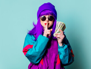 Stylish white girl with purple hair and 80s tracksuit hold cash money on blue background