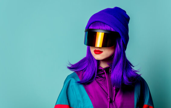 Stylish girl in cyber punk glasses and 80s tracksuit on blue background