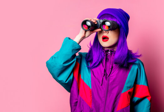 Stylish white girl with purple hair and 80s tracksuit using binoculars