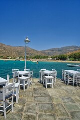 Fototapeta na wymiar Traditional wooden chairs and table in front of the famous mylopotas beach in Ios cyclades Greece