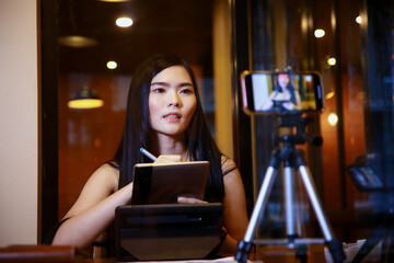 Fototapeta na wymiar Young asian woman vlogger recording video content for online channel.female looking at camera and talking on video shooting.content creator maker or social influencer concept