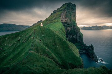 Lighthouse with steep cliffs during sunset on Faroese island Kalsoy, Faroe Islands.