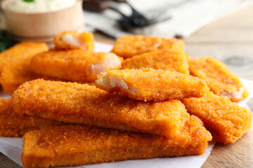 Tasty fresh fish fingers on wooden board, closeup