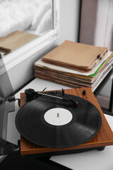 Stylish turntable with vinyl record on table indoors